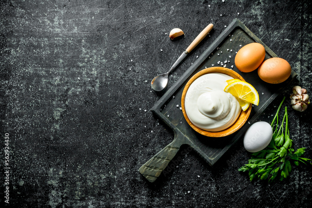 Poster mayonnaise on a cutting board with eggs, parsley, garlic and lemon slices.