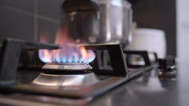 Man hand starting the gas burner for cooking dinner, blue flames
