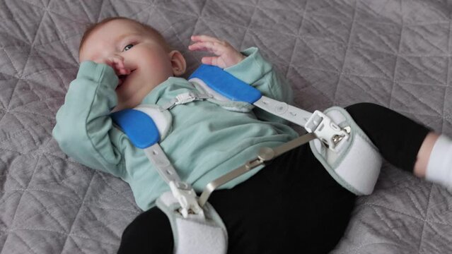 Close up of baby girl in Pavlik Harness to correct Hip Dysplasia on blanket