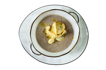 Appetizing mushroom cream soup with crispbread in a ceramic plate. Close-up. Top view. Isolated on white background.