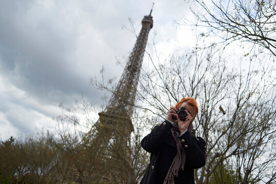 Low angle view of photographer using digital camera against Eiffel Tower