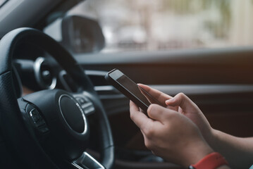A young businessman is using his smartphone in his car.