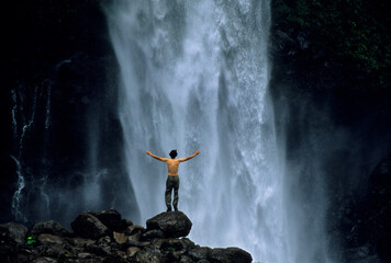 A man stands beneath the a waterfall on the Rio Verde in Ecuador.
