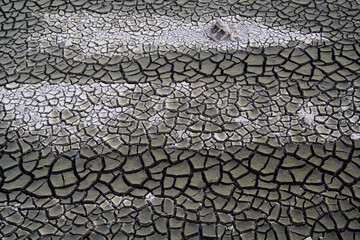 A cement block lies half-buried in the cracked mud in the floodplain of the Mino River below new Portomarin, Galicia, Spain.