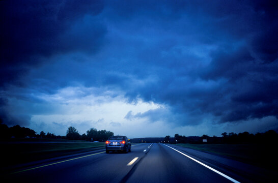 A late summer storm and dark threatening clouds makes driving on New Your Interstate 90 a challenging effort as a car passes out