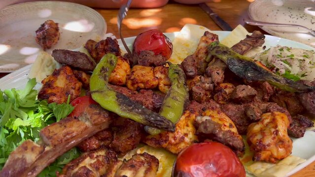 Eating a traditional Turkish big meat platter mixed grill with vegetables and fresh pide ekmek bread in Bodrum Turkey, authentic tasty food, 4K shot
