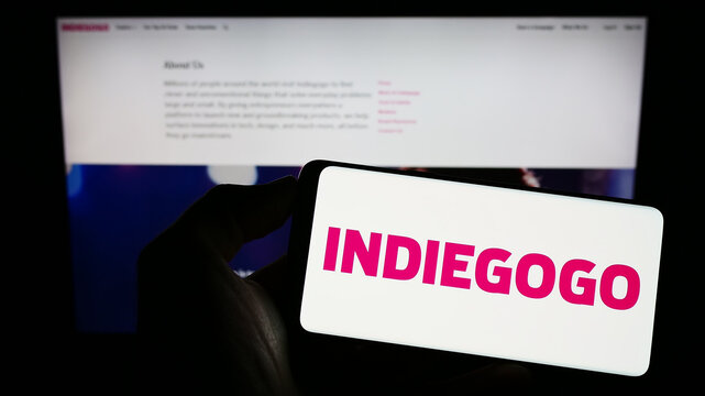 Stuttgart, Germany - 01-14-2023: Person holding mobile phone with logo of American crowdfunding company Indiegogo Inc. on screen in front of web page. Focus on phone display.