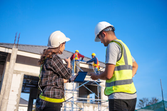 Construction inspector and female architect discuss with chief engineer Asia about installing solar panels on a construction project. Visit the construction site to install solar panels.