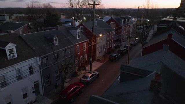 Aerial view of row houses at dusk. Person running on city street at night and walks into house.