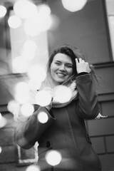 Close up smiling lady posing with bokeh lights monochrome portrait picture. Closeup front view photography with building on background. High quality photo for ads, travel blog, magazine, article