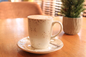 Obraz na płótnie Canvas Coffee in a ceramic mug on a saucer. The mug is white with brown spots. Delicious latte. Cozy cafe.