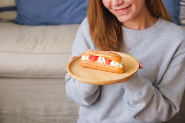 Closeup image of a woman holding a plate of strawberry Eclair