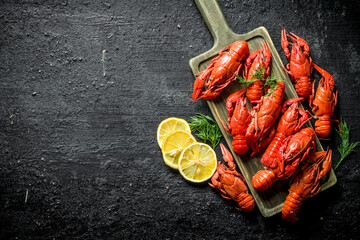Delicious Boiled crayfish on a cutting Board with sliced lemon and dill.