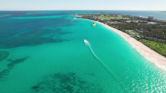 Paradise Island, Bahamas, Caribbean. 4K Aerial Panorama of a parasailer flying over emerald water.