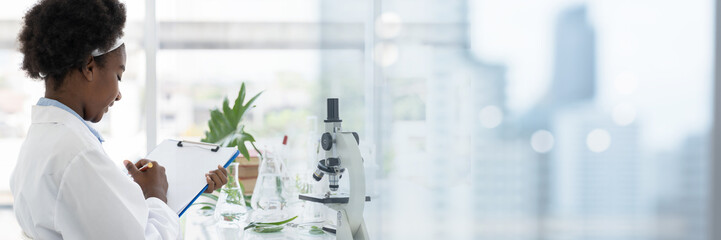 African American girl scientists researching through microscope in the laboratory. Scientific experiment. Early development of children