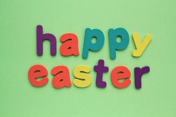 Obraz premium Happy Easter colored lettering on green background. Holiday spring compostion concept. Creative idea for greeting card, poster, banner, invitation, web sale. Top view, flat lay