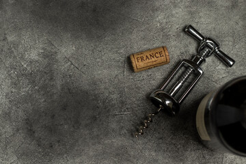 French wine. Bottle, corkscrew and cork on a black background.