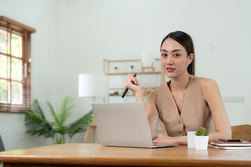 Portrait happy young asian girl working at home with a laptop