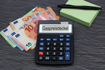 Das Wort Gaspreisdeckel ist auf dem Display eines Taschenrechners abgebildet mit Euro-Banknoten.  - obrazy, fototapety, plakaty