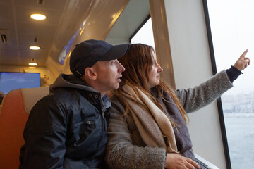 Woman and men traveling in the ferry enjoying view on the sea from the window