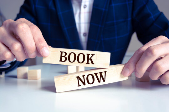 Close up on businessman holding a wooden block with "Book Now" message