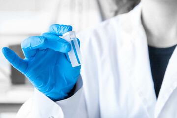 Close up scientist hand holding a spectrophotometry cuvette with blue gloves. Lab equipment for spectrophotometer. Education, development and science research. Horizontal copy space. 