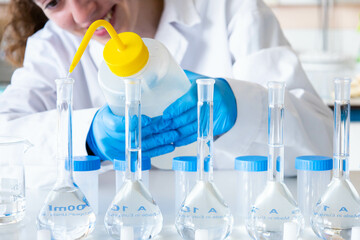 Close up scientist woman leveling a volumetric flask with a dropper wearing blue hand gloves and equipment. Happy lab girl technician working. Education, development and science research.