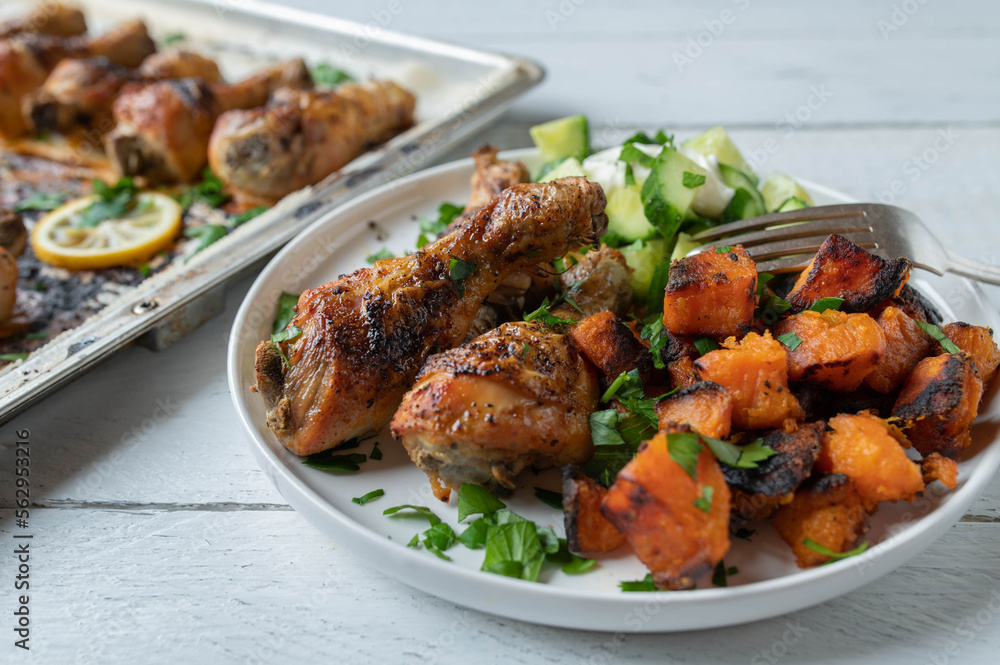 Wall mural Chicken drumsticks with roasted sweet potatoes and cucumber salad on a plate