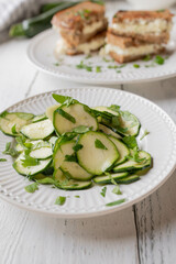 Zucchini salad marinated with olive oil, vinegar and honey. Served as a healthy sandwich side dish on white kitchen table. Front view