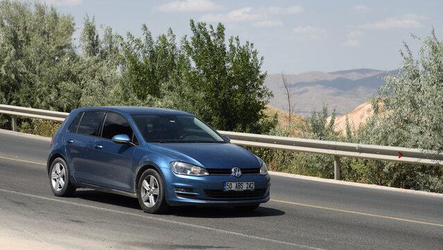 Cappadocia, Turkey 11.08.2022:A blue Volkswagen Golf VI is driving through the mountains of Cappadocia.