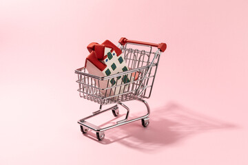Shopping cart and home model inside on pink background