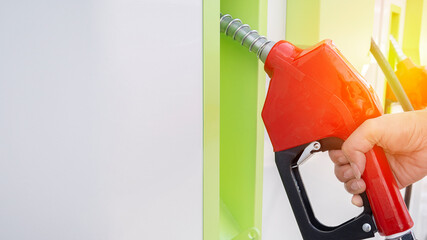 A gas station worker holds a fuel dispenser to fill the car with fuel.