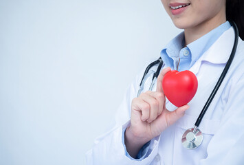 Female doctor with stethoscope and smile holding heart, isolated on white background.