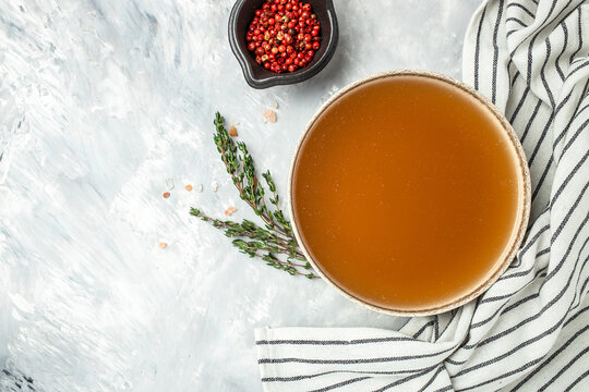 Bone Broth Bouillon in bowl with herbs and spices on a light background, banner, menu, recipe place for text, top view