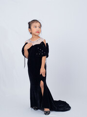 Closeup portrait of asian little girl in her black dress standing and posing in studio isolated on white background. 