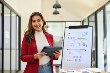 Confident Asian businesswoman stands in the meeting room with her tablet