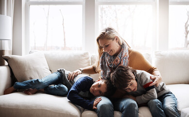 Happy family, mother bonding with children and relax on sofa for love, care and smile at home together. People, mom and kids lying on couch in the living room for cozy winter hug or fun with parent