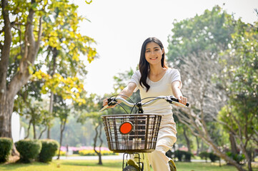 Charming Asian woman riding a bike in the public park in the afternoon. lifestyle concept