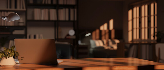 Comfortable office or home office with laptop, table lamp and decor on wooden table.