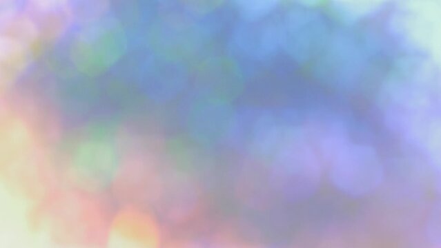 虹色に光り回転するラメとクリスタルのキラキラの薄いボケの背景  パステルカラー　春・美容・ジュエリーのイメージ