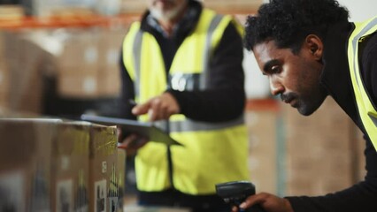 Warehouse trainee scans boxes with a barcode scanner under supervision of his manager, he learns how to record inventory into a warehouse management system using a tablet. Stockkeeping in logistics. - Powered by Adobe