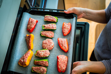 ピーマンの肉詰めをオーブンに入れる女性