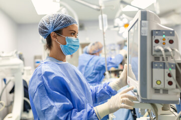 Anesthesiologist keeping track of vital functions of the body during cardiac surgery. Surgeon...