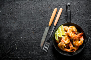 Freshly fried shrimps in a pan with slices of lime. - obrazy, fototapety, plakaty