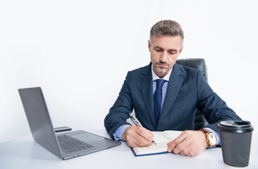 mature manager writing at the table in business office