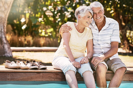 Senior couple, hug and swimming pool for summer vacation, love or relax spending quality bonding time together. Happy elderly man holding woman relaxing with feet in water by the poolside outside