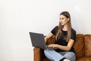 Beautiful woman with a laptop on a couch in a white isolated background
