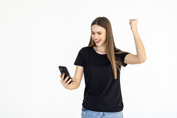 Naklejka premium Young woman winning on mobile phone, rejoicing and screaming of joy while using smartphone app, standing over white background