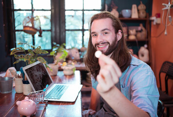 A young businessman owns a small pottery business. Are building themselves by saving money to expand their business in the future.