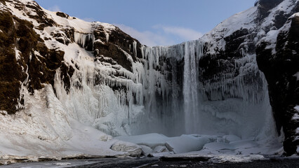 Fototapeta na wymiar The mighty Skogafoss waterfall all frozen in the middle of cold winter, South Iceland